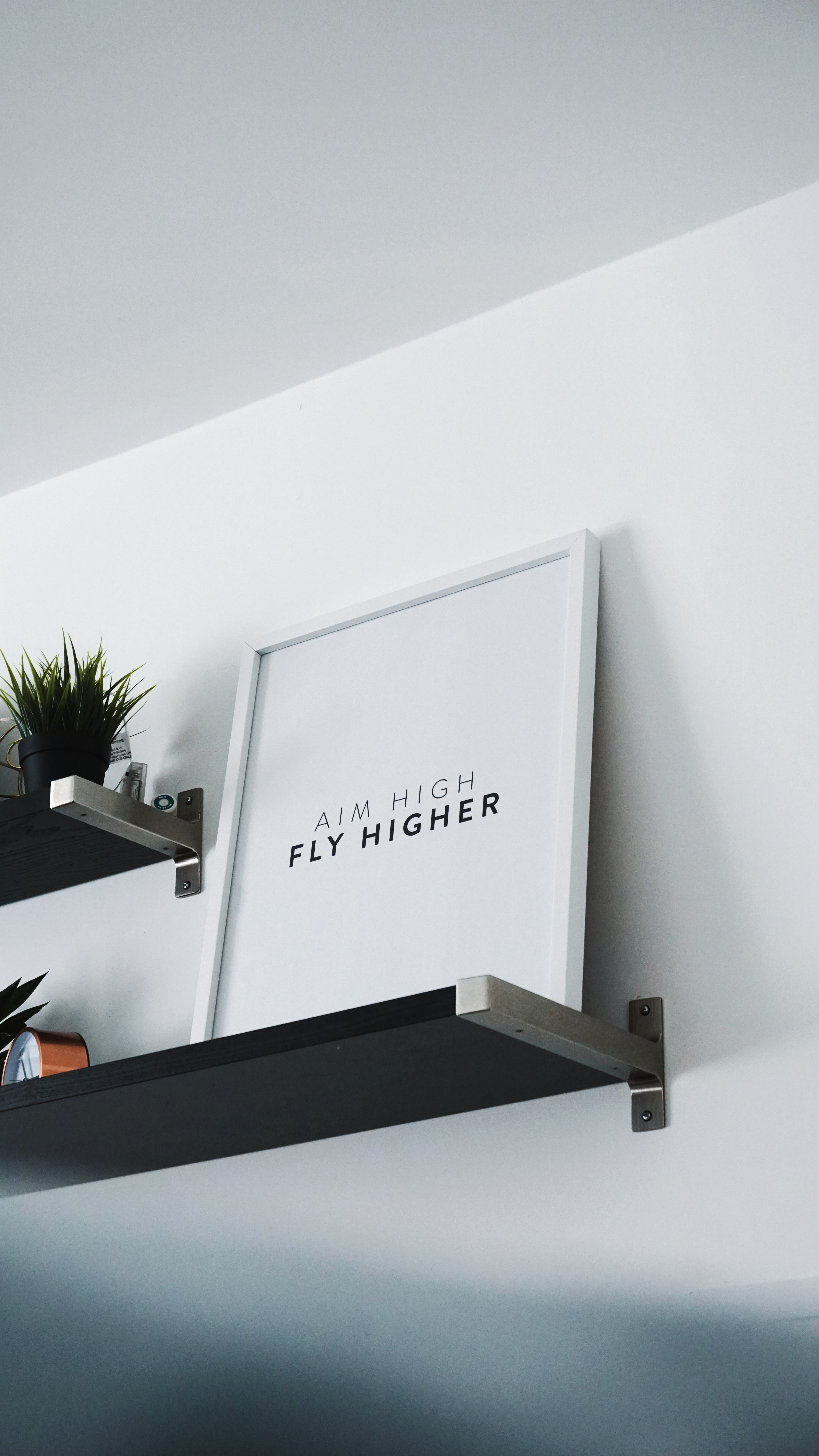 Image of wall art that says Aim High Fly Higher; Photo by  James Healy on Unsplash